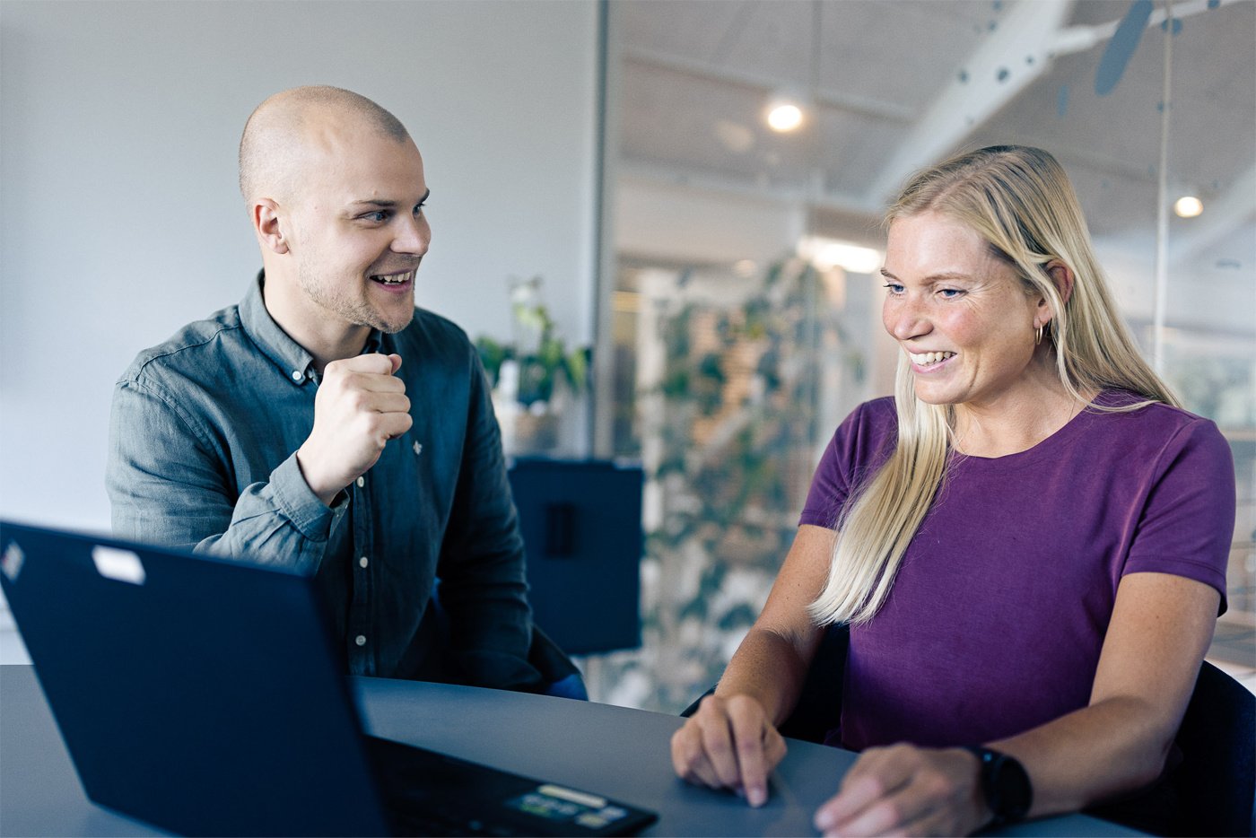 To medarbejdere i en engageret samtale foran en laptop – symboliserer personlig support og kundevejledning hos Plandisc